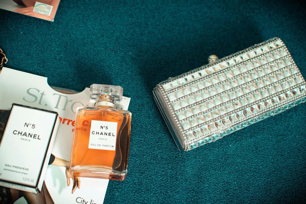 A luxurious setup featuring Chanel No.5 perfume beside a stylish silver clutch.